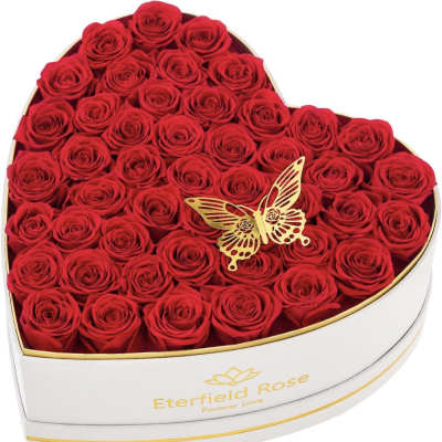 Heart-shaped box filled with red roses and a gold butterfly ornament