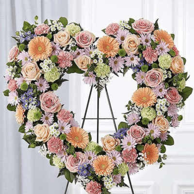 Heart-shaped floral wreath on an easel with pink, peach, and lavender blooms