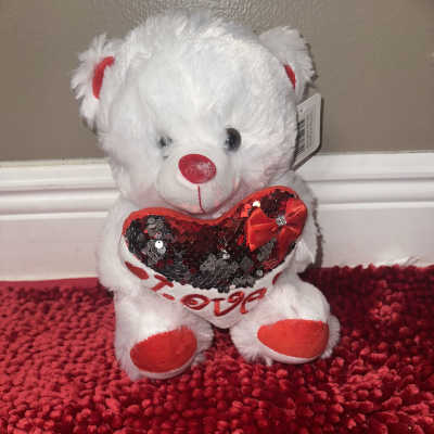 White plush teddy bear holding a red sequined heart