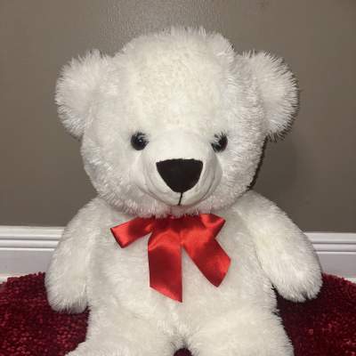 White teddy bear with a red ribbon bow