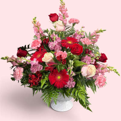 Mixed pink and red flower arrangement in a white vase