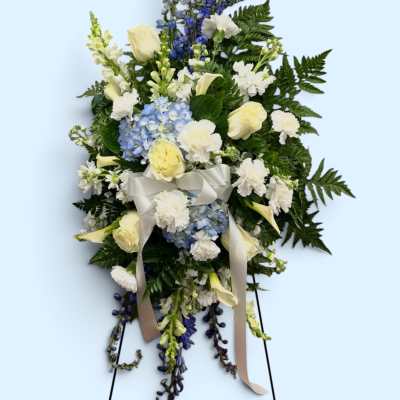 Standing floral spray with white roses, blue hydrangea, and ribbon