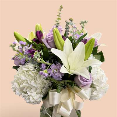 Lavender and white bouquet with lilies and roses in a glass vase