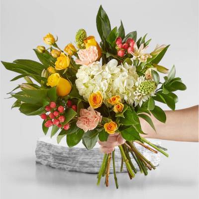 Handheld bouquet of yellow and peach flowers with white hydrangea