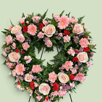 Heart-shaped floral wreath with pink roses, carnations, and daisies