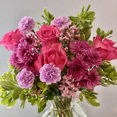 Pink roses and purple flowers in a clear glass vase