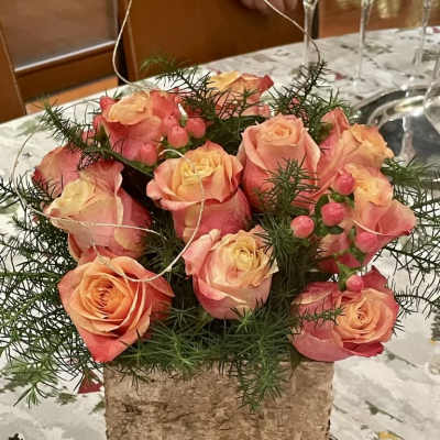 Pink and peach roses arranged in a birch bark container