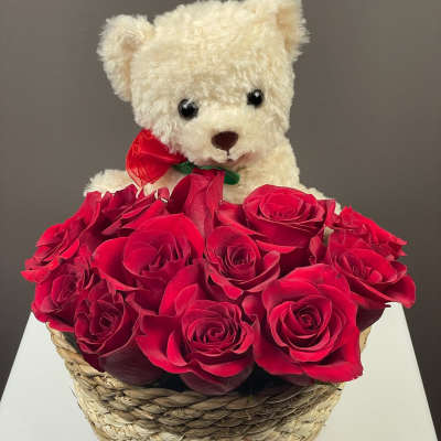 White teddy bear in a basket of red roses