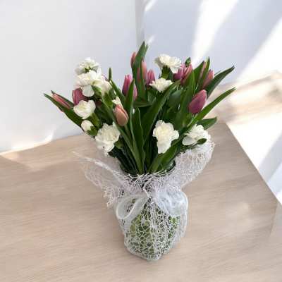 Bouquet of pink tulips and white carnations in a wrapped vase