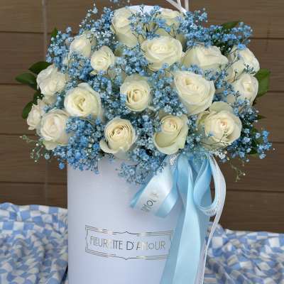 White roses and blue baby's breath in a white hatbox with ribbon
