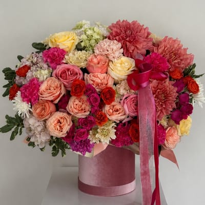 Large pink and peach flower arrangement in a velvet hatbox with ribbon