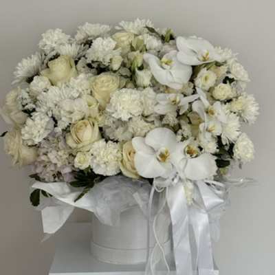 White floral arrangement in a round hatbox with ribbon