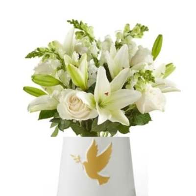 White lilies and roses in a white vase with a dove emblem