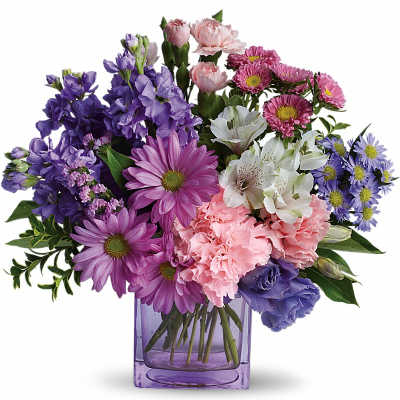 Mixed purple, pink, and white flowers arranged in a purple glass vase