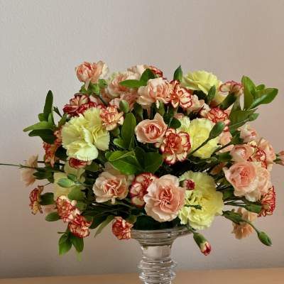 Mixed carnations and peach spray roses in a clear glass vase