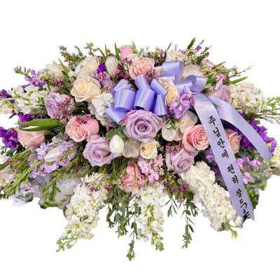 Large pastel floral spray with roses and white blooms, tied with a lavender ribbon