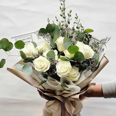 Bouquet of white roses with eucalyptus in tan wrapping