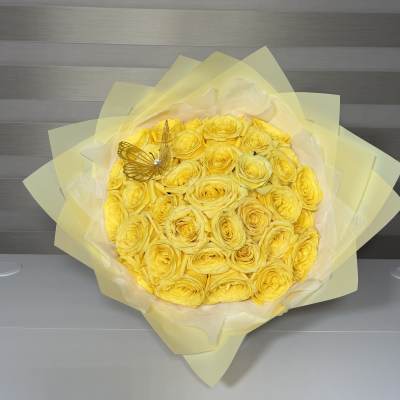 Bouquet of yellow roses wrapped in pale yellow paper with a butterfly decoration