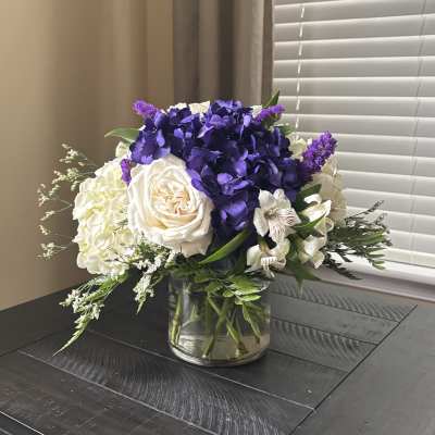 Purple and white floral arrangement in a clear glass vase