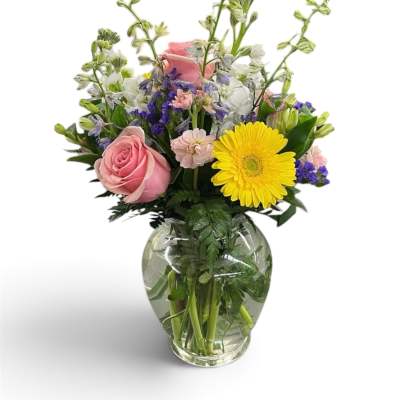 Mixed bouquet in a clear glass vase with pink roses and a yellow gerbera daisy