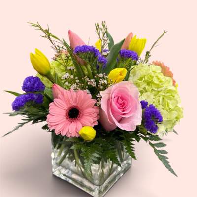 Mixed bouquet in a square glass vase with pink and yellow blooms