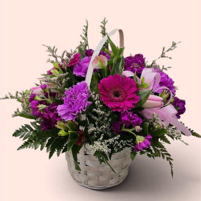 Basket of purple flowers with a pink gerbera daisy and ribbon