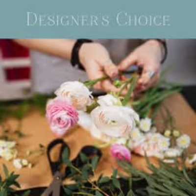 Hands arranging pink and white ranunculus flowers on a table