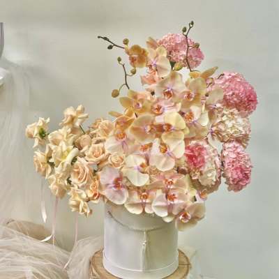 Peach orchids and pink hydrangeas arranged in a white hatbox