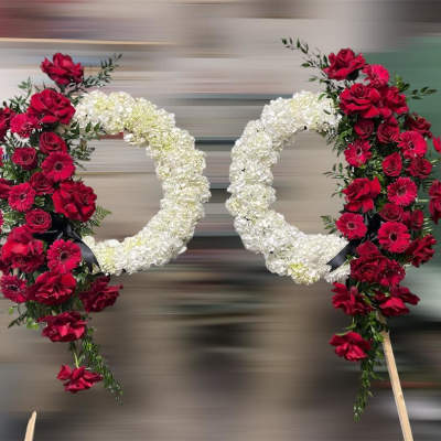 Two floral wreaths with red roses and white flowers on stands