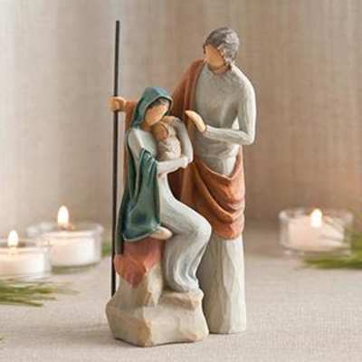 Wooden nativity figurine of Mary, Joseph, and baby Jesus with candles nearby