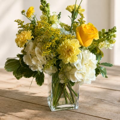 Yellow and white floral arrangement in a clear glass vase