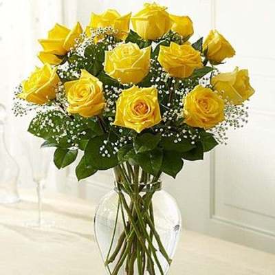 Yellow roses arranged in a clear glass vase with baby's breath