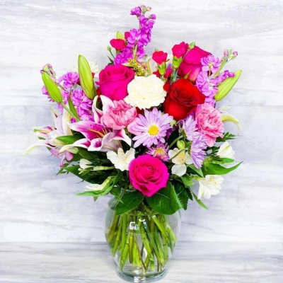 Mixed pink, purple, and white bouquet in a clear glass vase