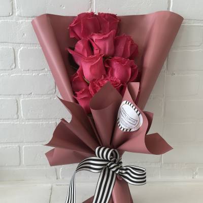 Bouquet of hot pink roses wrapped in dusty pink paper with a striped ribbon