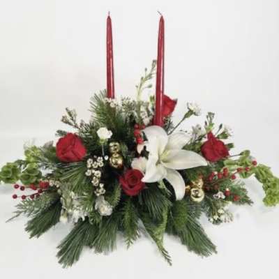 Holiday floral centerpiece with red candles, white lily, and red roses