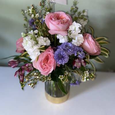 Pink roses and purple flowers arranged in a metallic vase
