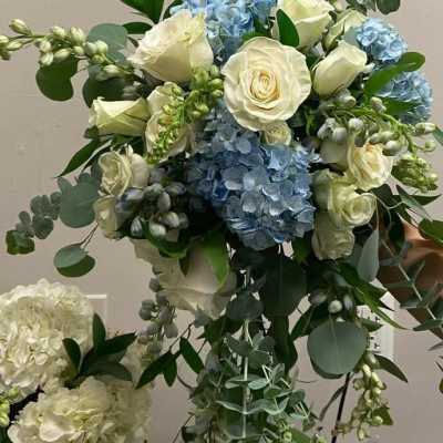 Bouquet of white roses and blue hydrangeas with mixed greenery