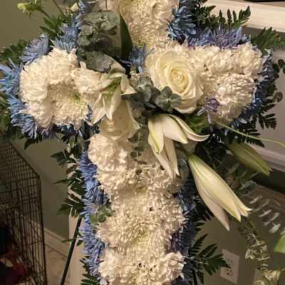 Standing floral cross with white and blue flowers on an easel