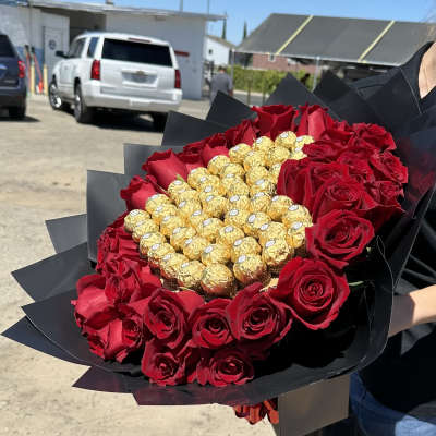 Bouquet of red roses surrounding gold-wrapped chocolates