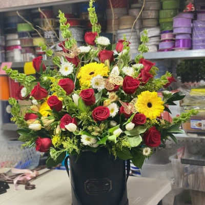 Bouquet of red roses and yellow gerbera daisies in a black hatbox