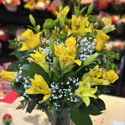 Yellow lilies and roses in a clear glass vase