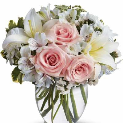 Pink roses and white lilies arranged in a clear glass vase