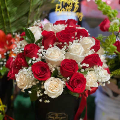 Red and white roses arranged in a black hatbox with a birthday topper