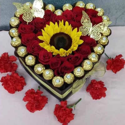 Heart-shaped bouquet of red roses with a sunflower center and gold-wrapped chocolates