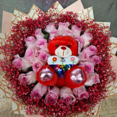 Pink rose bouquet with a red teddy bear in the center