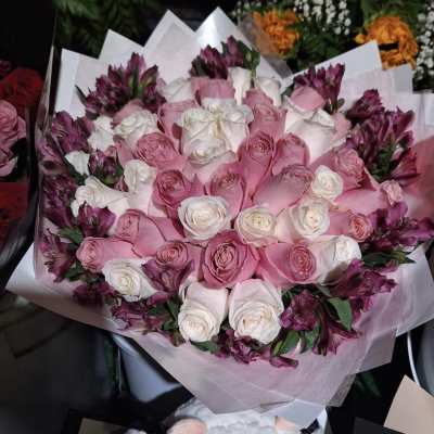 Bouquet of pink and white roses with purple flowers wrapped in pale paper