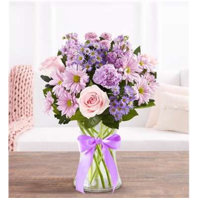 Pink and lavender bouquet in a clear glass vase with a purple ribbon