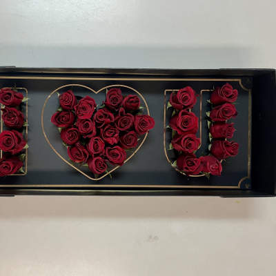Red roses arranged to spell "I ♥ U" in a black tray