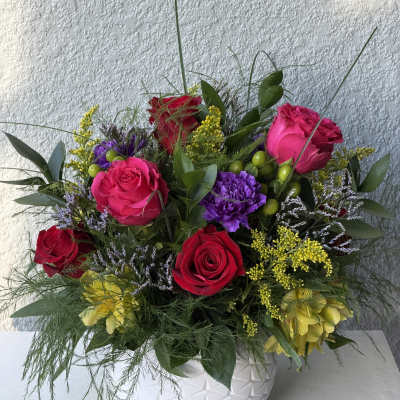 Colorful rose arrangement in a white textured vase with mixed filler flowers