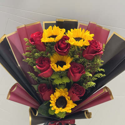 Bouquet of red roses and yellow sunflowers wrapped in black and burgundy paper
